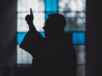 Silhouette di un uomo vicino a una vetrata di chiesa, luce calma