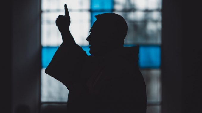 Silhouette di un uomo vicino a una vetrata di chiesa, luce calma
