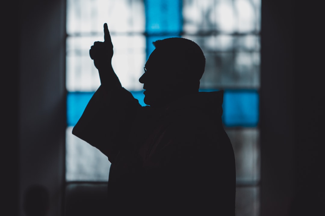 Silhouette di un uomo vicino a una vetrata di chiesa, luce calma